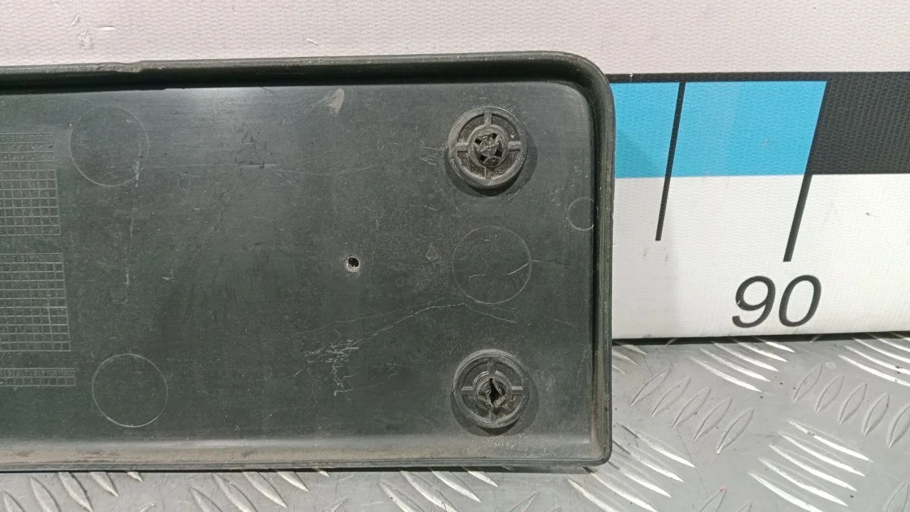 [Б/У] Накладка переднего бампера под гос номер - Отверстия от шурупов [Незначительные дефекты] [Код: 00381298 ]