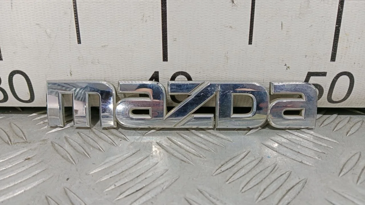[Б/У] Эмблема на крышку багажника Mazda 5 (CR) - Эмблема "MAZDA" [Код: 00397704]